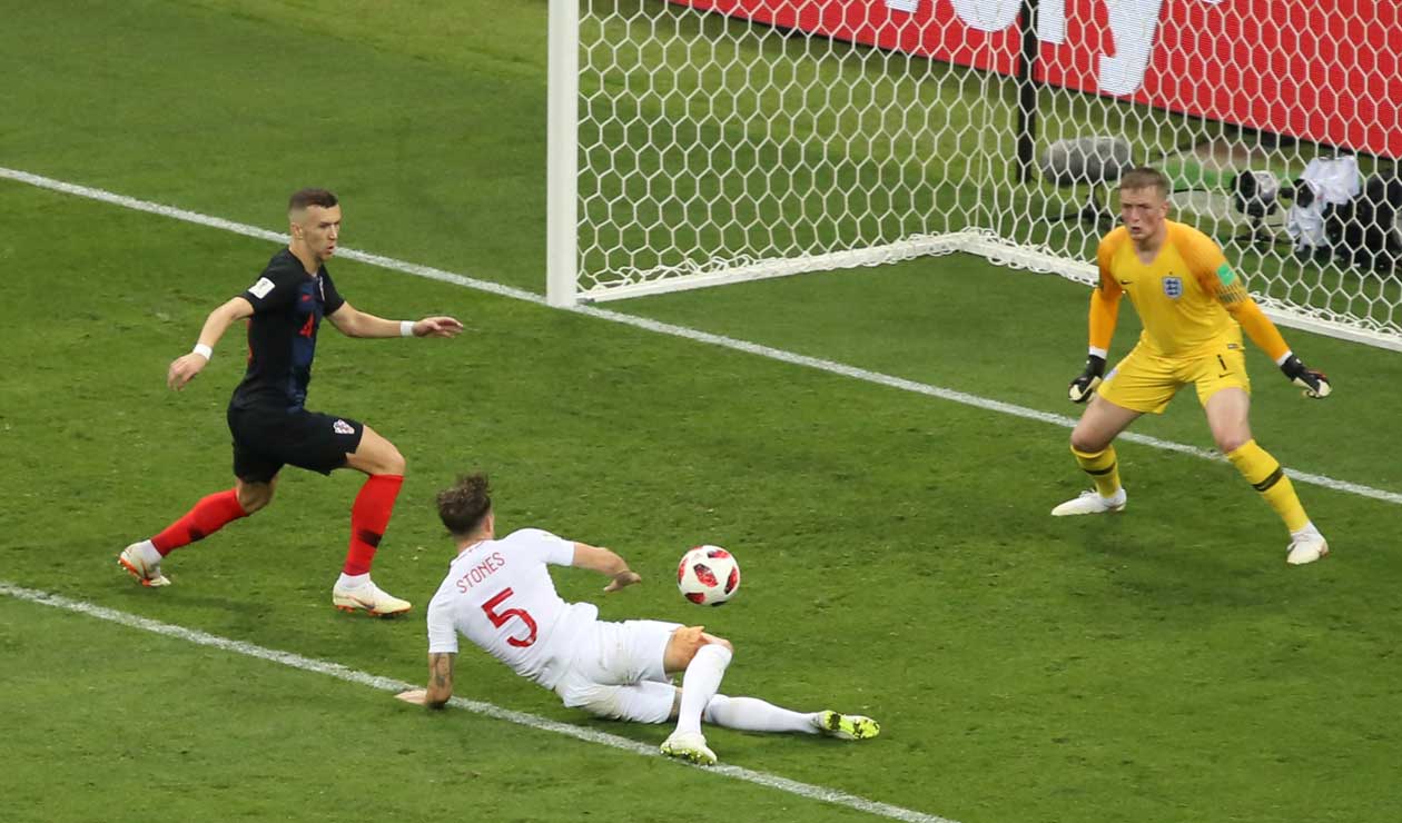 John Stones intenta rechazar un balón ante la presión de Ivan Perisic