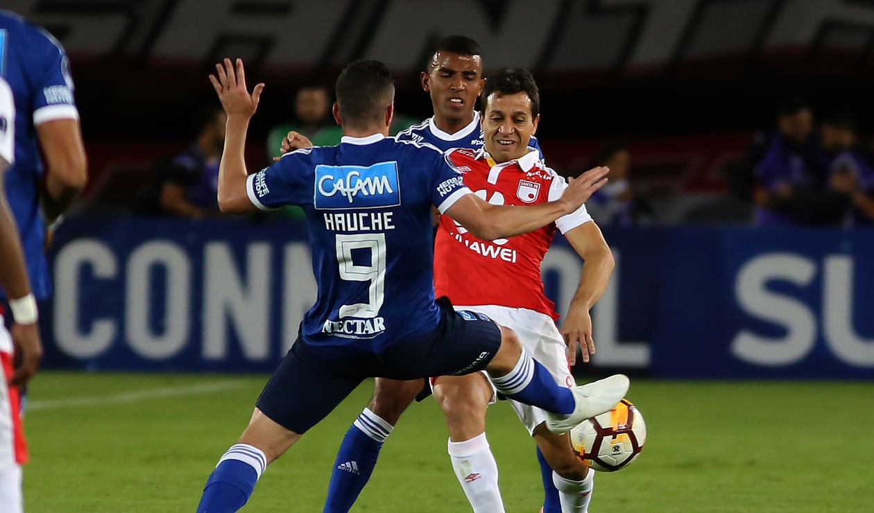 Diego Güastavino (Santa Fe) ante la marca de dos jugadores de Millonarios 
